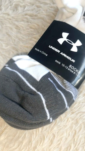 Under Armour white and black athletic socks with logo and striped design.