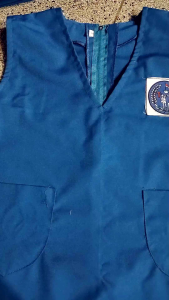 Seragam TK nasional anak perempuan warna biru hijau merah dan oranye atasan tanpa lengan kain famatek dengan saku depan dan logo di dada.