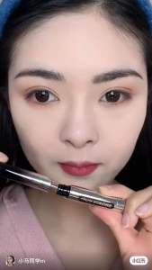 Black mascara with silver tube and brush. Thick dark pigment. Long curled lashes. Close-up of eye and hand.