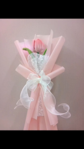 Bó hoa tulip hồng đơn trang trí với giấy gói màu hồng nhạt và ruy băng trắng.