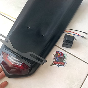 CRF150L Undernet fiber complete set lights and plate holder. Red molded plastic with black light fixture and mounting bracket. Motorcycle body and frame accessory.