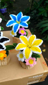 Mini flower in a pot made of fuzzy wire available in different colours. Purple pink blue black yellow white daisy lily. Indoor decorative plant.