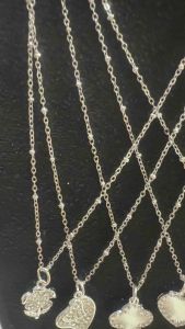 Silver chain necklace with four-leaf clover pendant. Thin chain intricate clover design silver finish pendant with floral pattern elegant accessory.