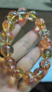 LITTLE D KOI FISH QUARTZ NATURAL CRYSTAL BRACELET - Transparent beads with orange and pink hues spherical shape elastic band. Worn on wrist.