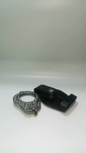 Black leather handcuff key holder with silver handcuffs. Key attributes: textured leather metallic handcuffs snap button closure. Fit/use: key storage accessory. Scene: hand holding the item.