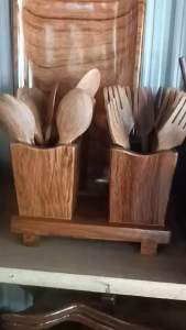Wooden utensil set with spoons forks and holder in two compartments on a wooden tray.