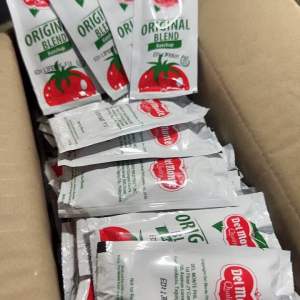 Del Monte Original Blend Ketchup 10g sachet white packaging red tomato graphic green text food staples cooking sauces.