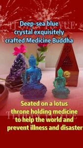 Blue and green translucent Buddha statues on a white surface with purple crystals and wooden incense holder in background.