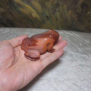 Agate frog figurine with striped patterns and glossy finish. Handheld decorative item.