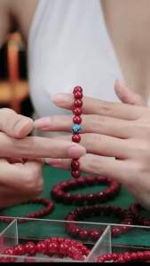 Vòng tay chu sa hạt đỏ và trắng với mặt dây chuyền vàng.