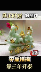 Green jade three goats with golden accents on a decorative base.