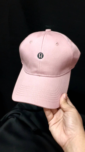 Lululemon pink baseball cap with logo on front. Adjustable strap. Casual sporty accessory.