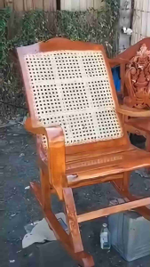 Wooden armchair with woven cane backrest and seat. Polished finish. Located in living room with sofa and cabinet.