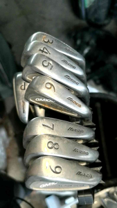 The image displays a set of used Mizuno GM100 golf irons. These are mens right-handed clubs designed for game improvement and feature a T.L. Flow System and cavity back design.