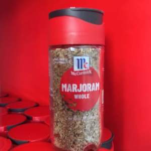 McCormick Marjoram Whole 8g Small Bottle - Red cap transparent body visible herbs red label with white text stacked on red surface.