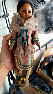 Vintage Indian Girl Doll with Fur Trimmed Outfit Holding a Bag in a Workshop Setting