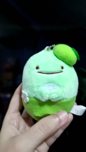 Sumikko Charms Green Plushie with hat and flower keychain. Soft plush toy with smiling face green hat flower accessory and keychain attachment. Suitable for keychain use or display.