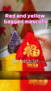 Red and yellow drawstring pouches with Chinese characters. Red pouch features large gold character. Yellow pouch has smaller gold characters. Both placed on white surface with decorative background.