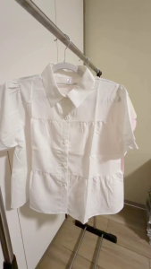 Short-sleeve blouse with puffed sleeves and peplum hem. Collared design with button front.