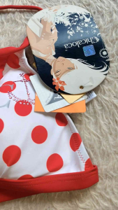 White bikini top with red polka dots and ruffles Adjustable halter neck straps Decorative bow on one cup Brand tag visible