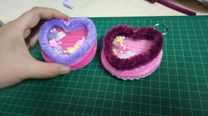 Heart-shaped keychains with fuzzy borders and transparent centers filled with colorful beads and charms.