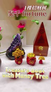 Golden money tree figurines in red pots with Chinese characters placed on a white surface with an amethyst crystal and a wooden box in the background.