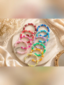 Colorful beaded bracelets with silver chains on marble surface.