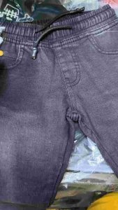Denim Kids Jogger Pants Overruns Made in Bangladesh. Blue color drawstring waist pockets tags attached. Casual wear for kids. Displayed on a white surface.