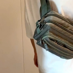 Black waist bag with multiple zippered compartments adjustable strap and orange stitching