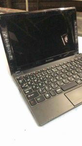 Laptop Lenovo màu đen với logo trắng kích thước đo bằng thước đặt trên bề mặt nhựa trắng. Bán xác nghe