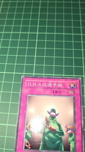 YUGIOH DNA Surgery (N) Japanese CA-26 DL1-114 SK2-035 BE1 Trading Card Game Card. Two cards displayed on a green grid surface.