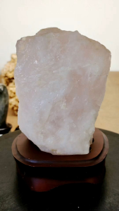 Natural Brazil Rose Quartz Crystal Rough Stone Ornament RB02 on wooden stand light pink color irregular shape smooth texture decorative home decor item.