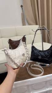 Túi Chanel màu nâu trắng đen với khóa kim loại và dây xích.