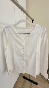 White blouse with V-neck and button front three-quarter sleeves with ruffled cuffs textured fabric.