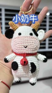 crocheted cow amigurumi which is a small stuffed yarn toy. It appears to be handmade and could be used as a keychain or decorative item