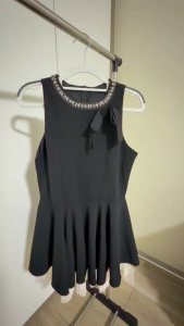 Black sleeveless dress with flared skirt and white tulle hem. Bow detail on shoulder.