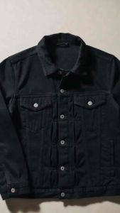 Blue denim jacket with button closures and chest pockets. Layered over a black shirt.
