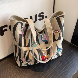 กระเป๋าผ้าใบทรงโตที่มีความจุขนาดใหญ่สำหรับผู้หญิง กระเป๋าสะพายไหล่แบบลำลองสำหรับใส่ไปเรียน กระเป๋าผ้าใบลายตัวอักษรใหม่ ปิดด้วยซิป ปิดด้วยซิป