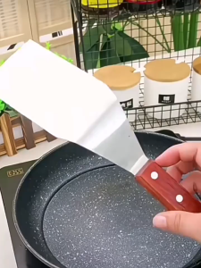 Stainless steel cooking spatula with wooden handle. A cooking accessory.