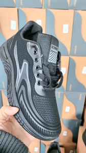 Black athletic sneakers with mesh upper and white accents. Suitable for casual wear and light exercise. Displayed outdoors on a metal surface.
