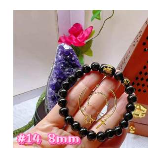 Black beaded bracelet with gold star charm and red accent bead.