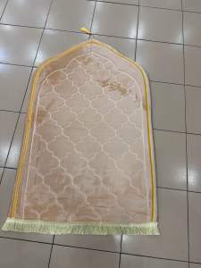 Brown embroidered prayer mat with name "Yusmin" and decorative tassels.
