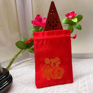 Red and yellow drawstring pouches with Chinese characters. Red pouch features large gold character. Yellow pouch has smaller gold characters. Both placed on white surface with decorative background.