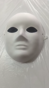 White round mask with eye holes and elastic straps on plastic surface.