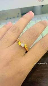 Gold ring with diamond accents and wave design. Worn on finger with keyboard in background.
