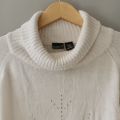 Sweater turtleneck oversize putih. 