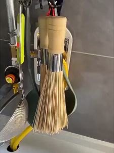 Bamboo wok brush with wooden handle and metal ferrule for cleaning woks.