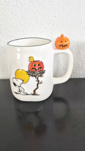 2025 Peanuts Worldwide LLC and Rae Dunn irregular-shaped Halloween Snoopy mug with pumpkin on handle (Woodstock in pumpkin)