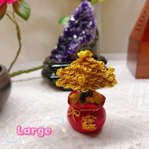 Golden money tree figurines in red pots with Chinese characters placed on a white surface with an amethyst crystal and a wooden box in the background.