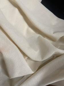 Cream-colored lightweight fabric with subtle sheen and soft texture. Suitable for clothing or home decor.